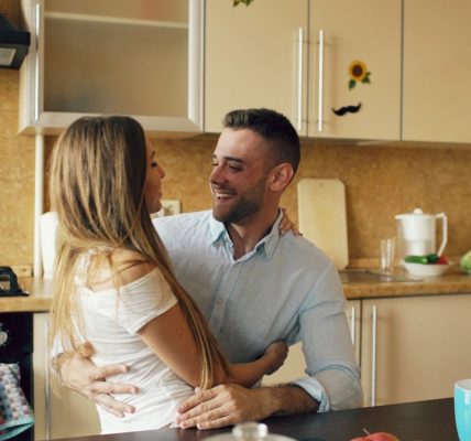Attractive young couple embracing early morning in the kitchen.