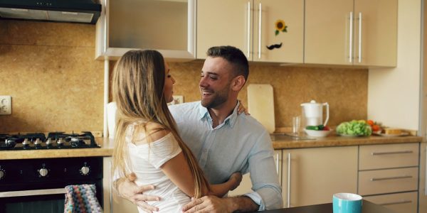Attractive young couple embracing early morning in the kitchen.